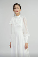 Elegant floor-length silk dress with sheer sleeves and high neck bow detail